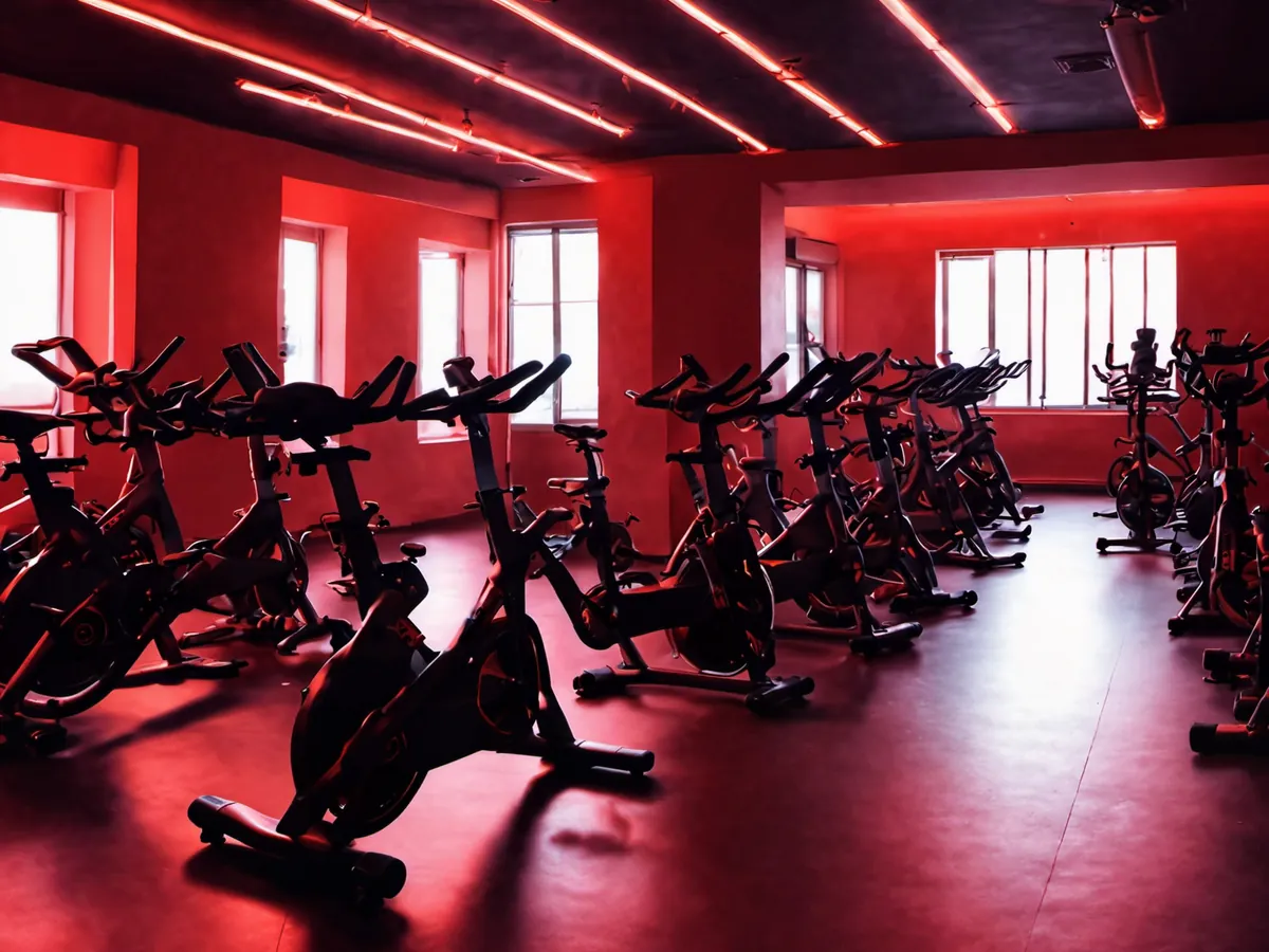 A dark spin studio with rows of bikes under neon lights