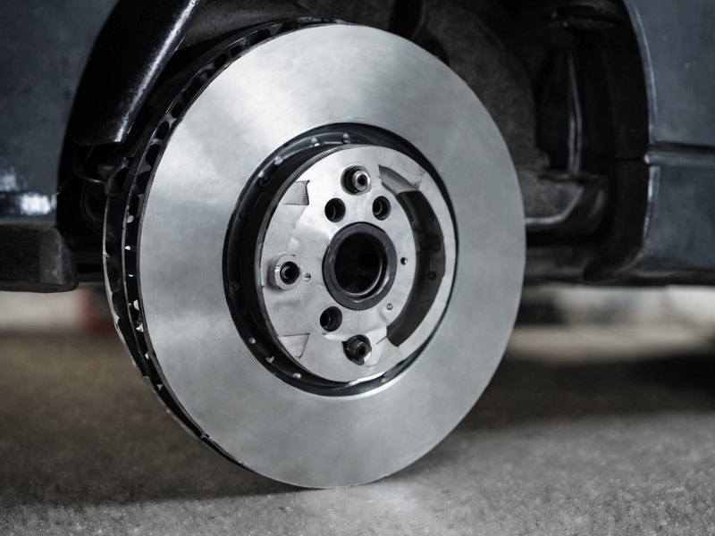 Close-up of a brake disc and caliper on a raised car